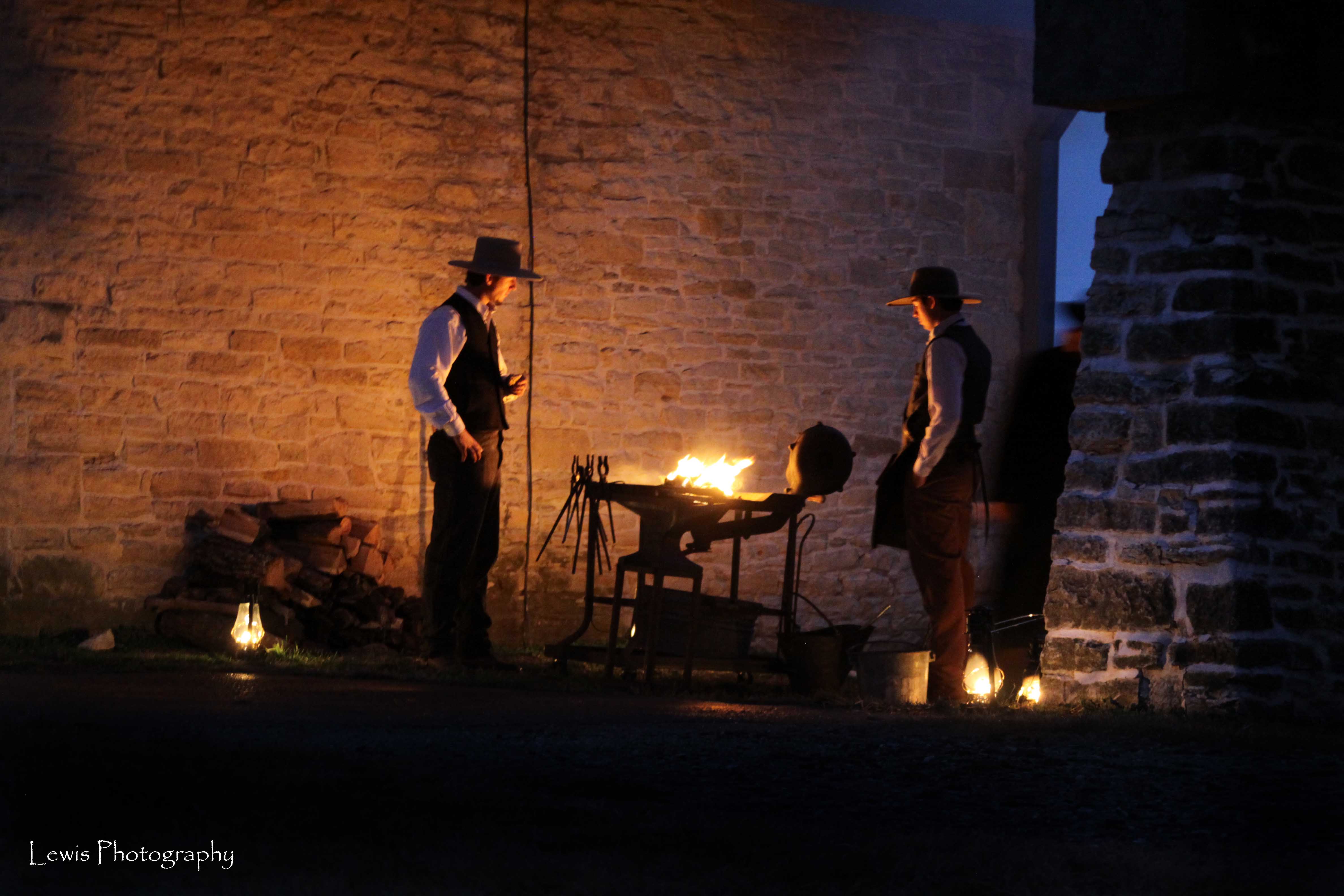 cowboys working hot metal in the forge among lantern light