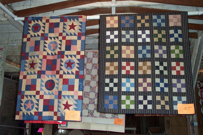 quilts hanging from rafters in a barn