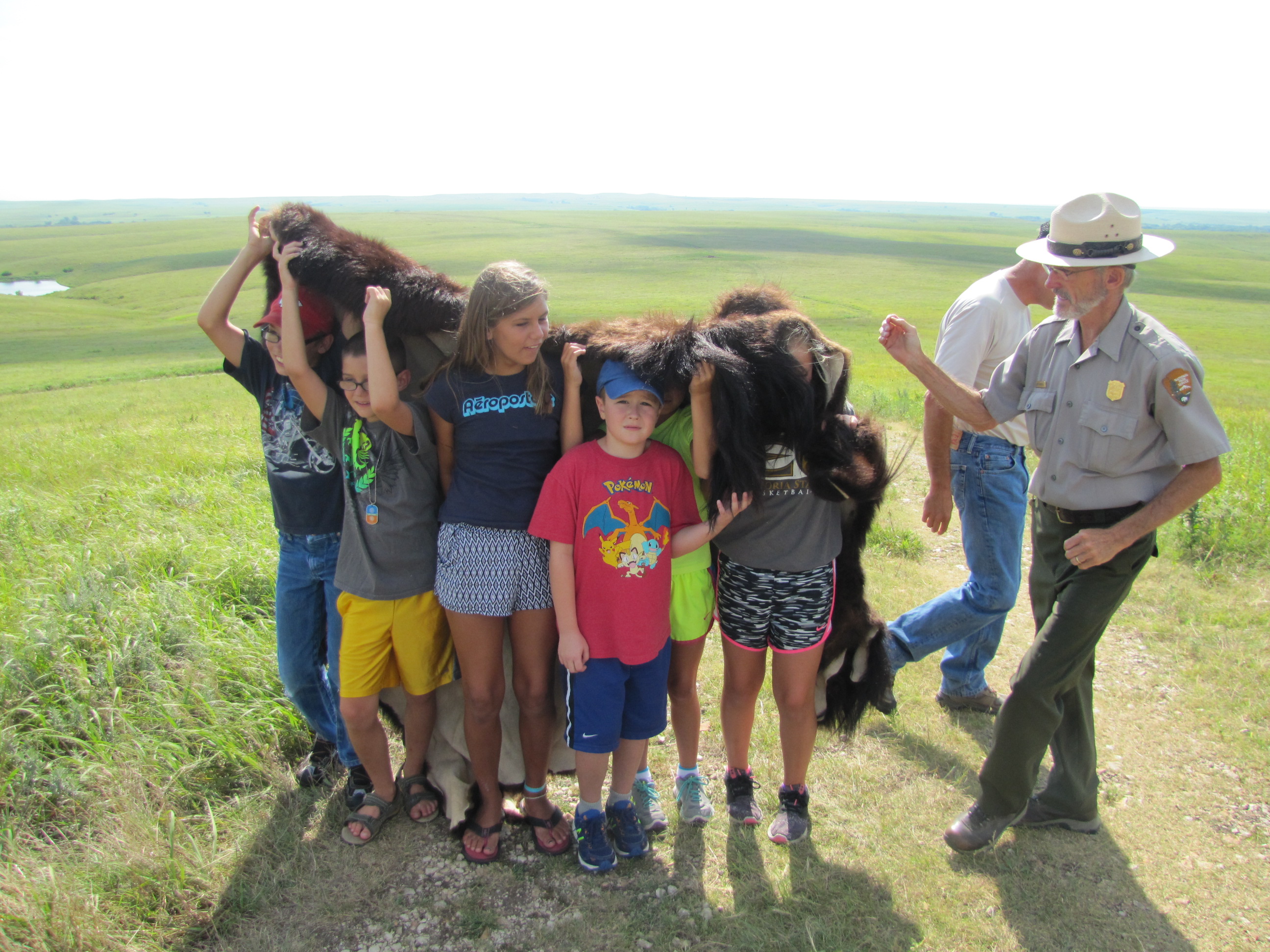 Kids wear a bison robe to simulate bison in the prairie