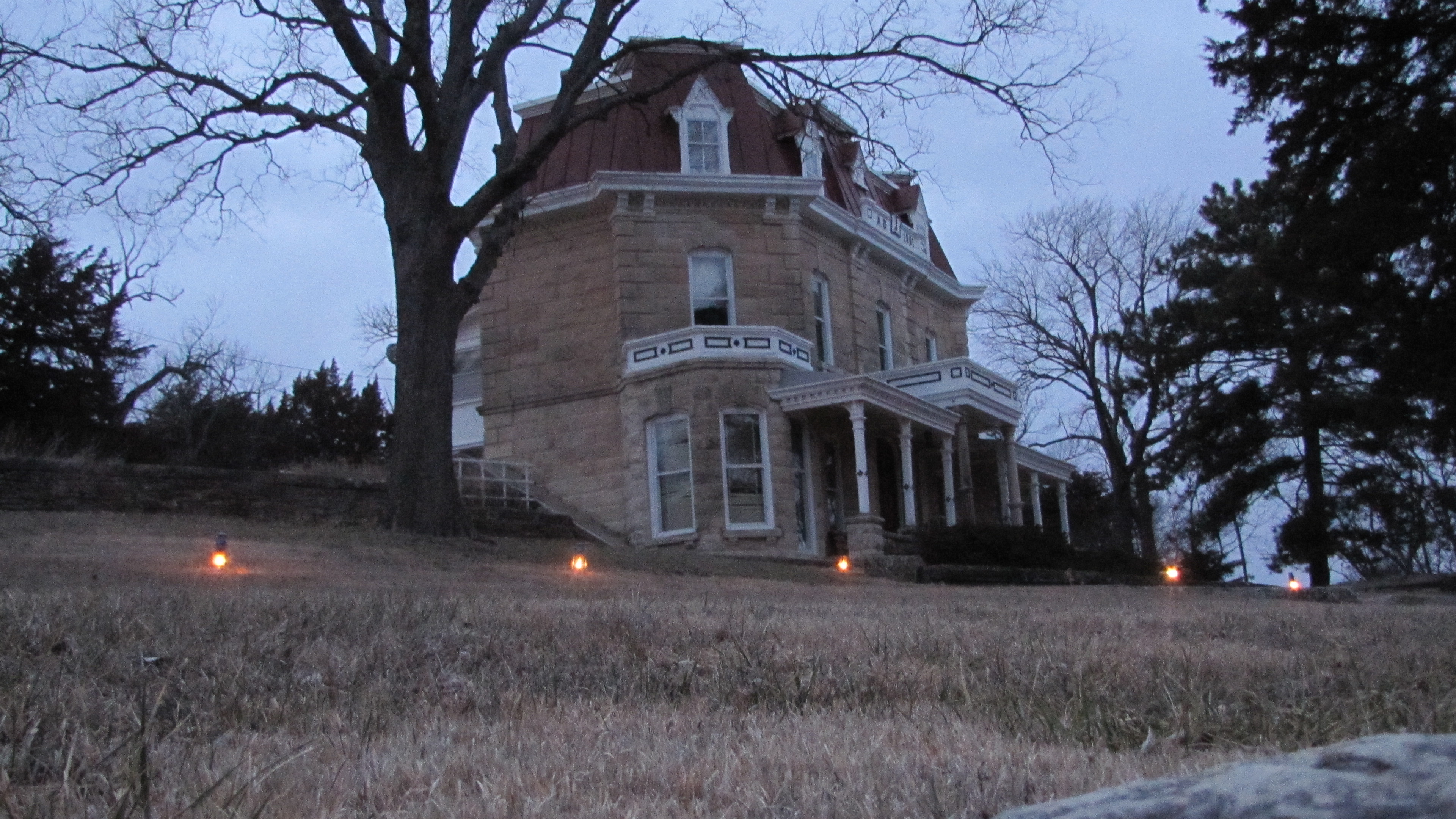 Historic 3-story limestone mansion with lanterns lighting the pathway