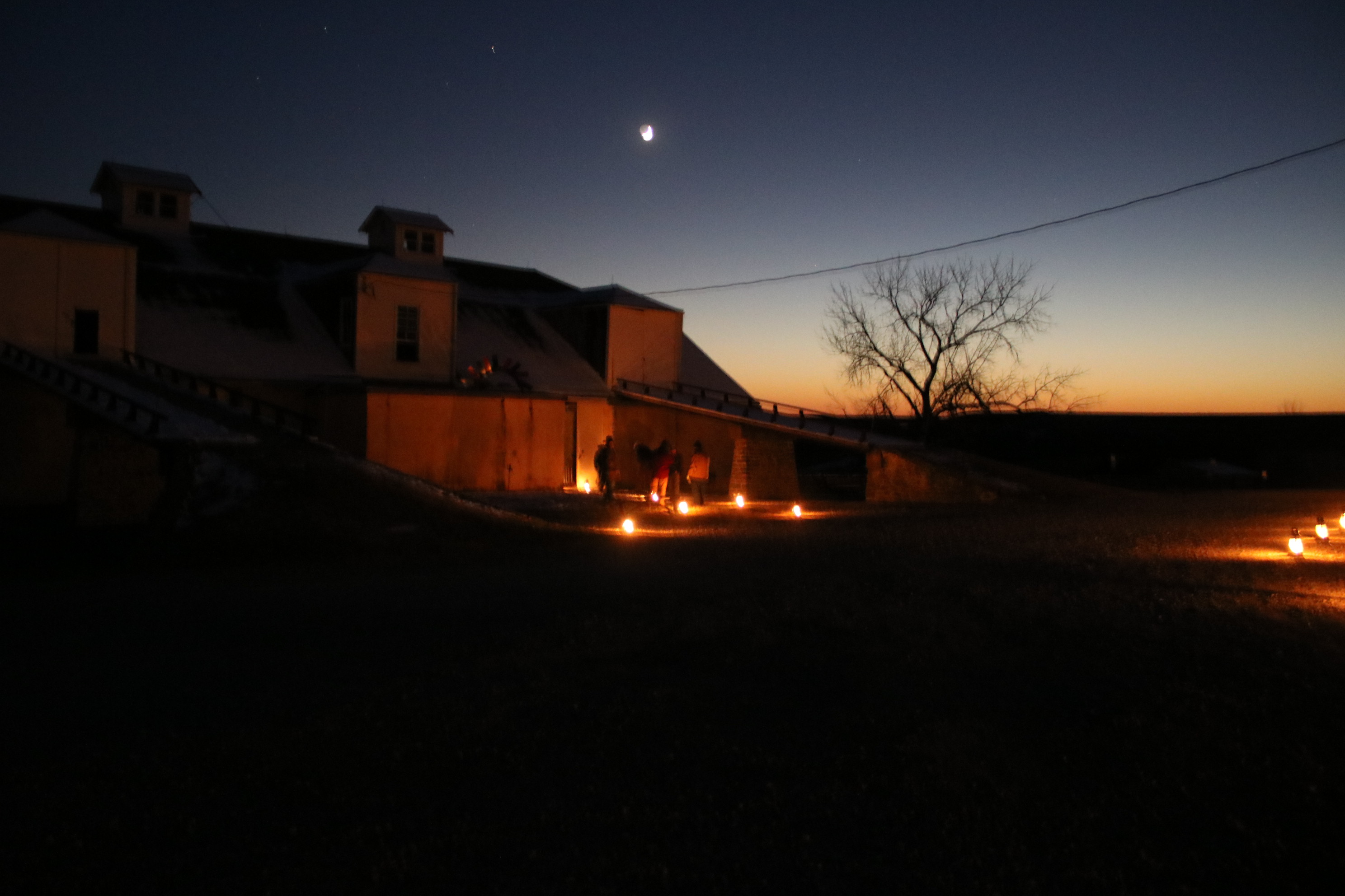 Historic barn at night with lanterns lighting path