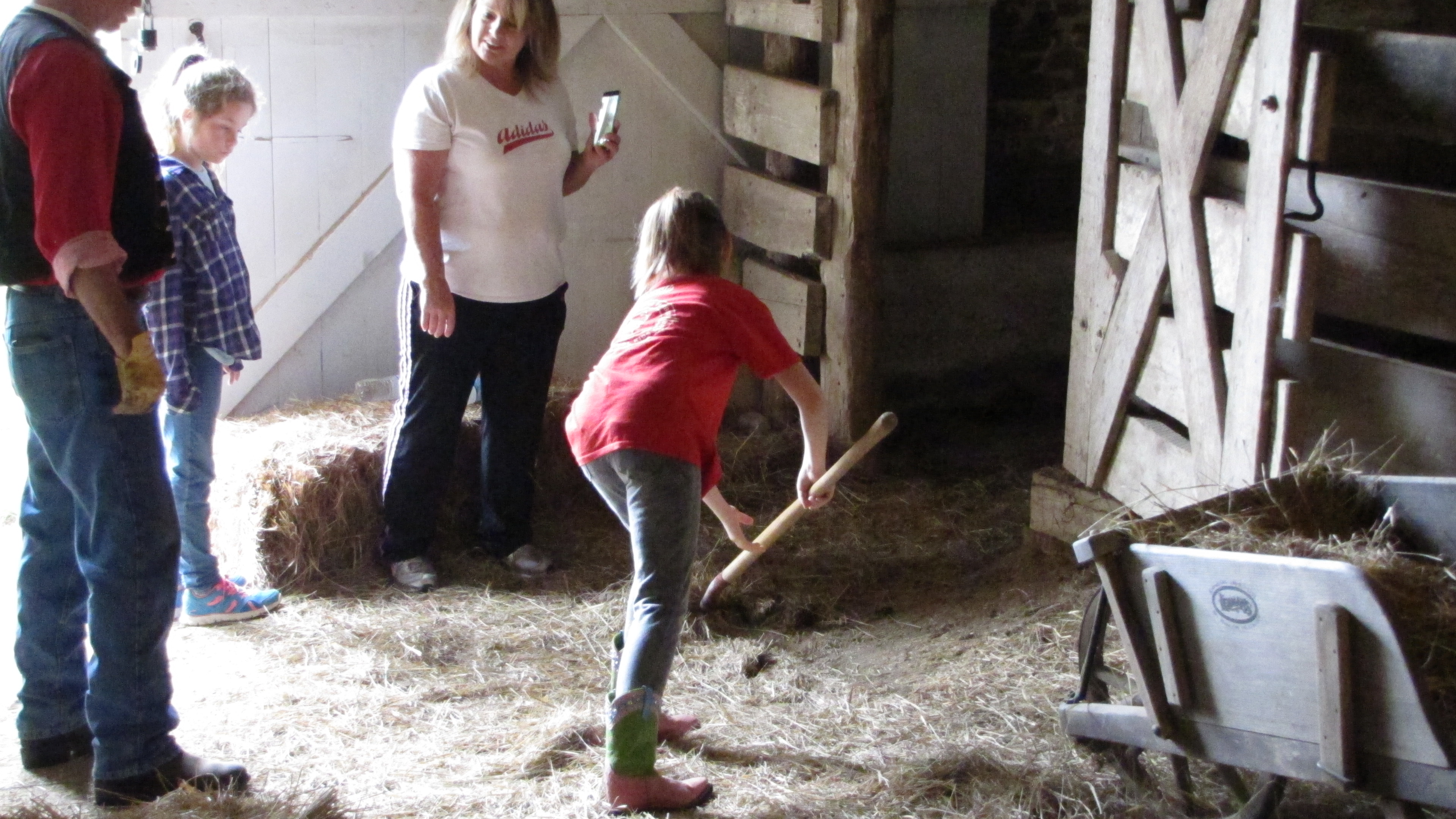 Kids doing chores in the barn using a pitch fork