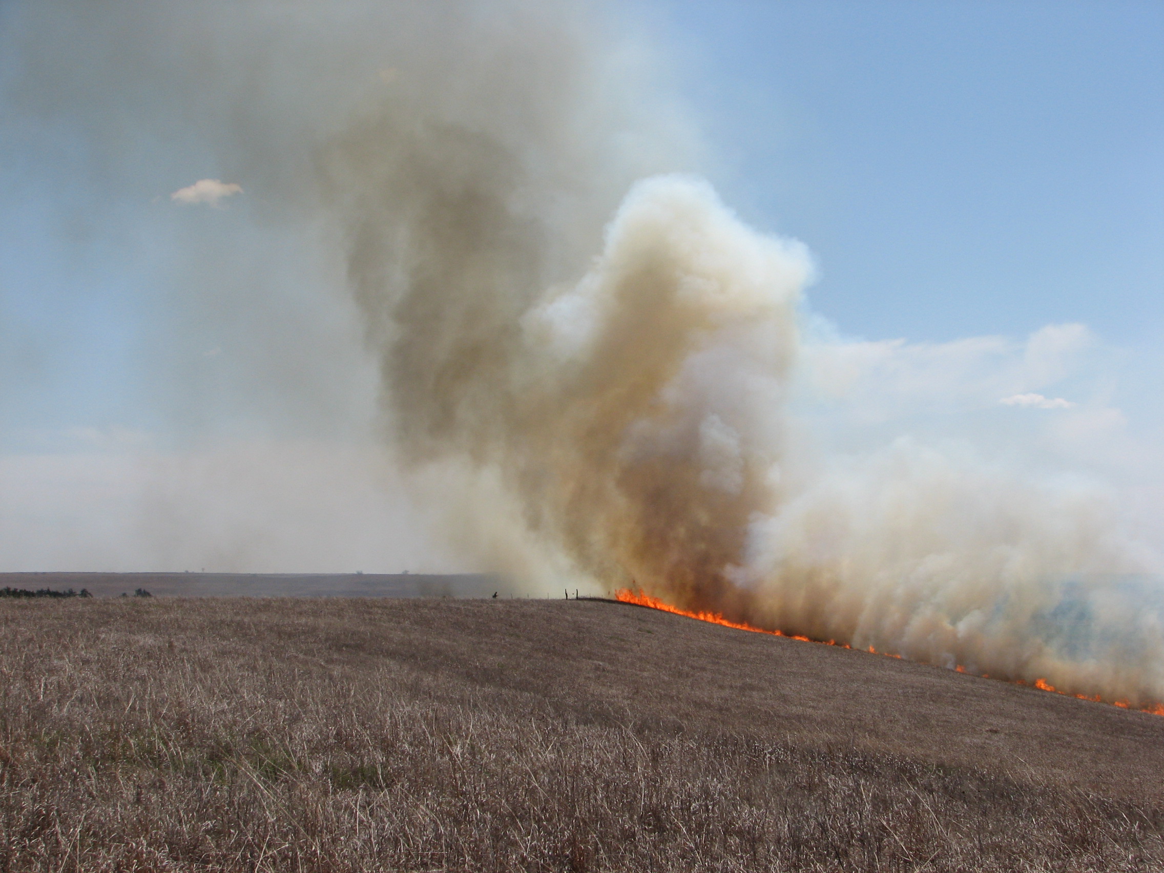Fire and smoke on horizon during a controlled burn on the prairie