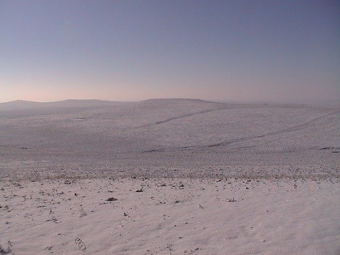 Snow covers rolling prairie hills