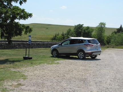 Vehicle parked diagonally in the parking area near barn. Look for two blue and white placard signs.