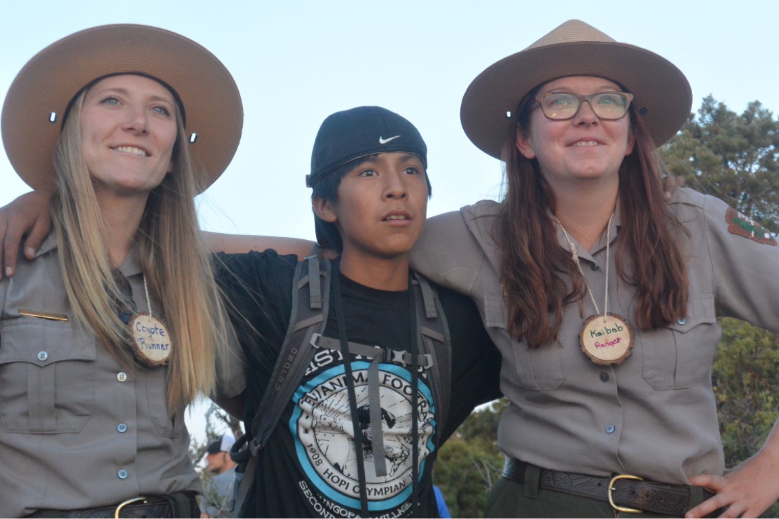 Two rangers and a junior ranger look out over a Grand Canyon sunset. Two rangers and a junior ranger look out over a Grand Canyon sunset.