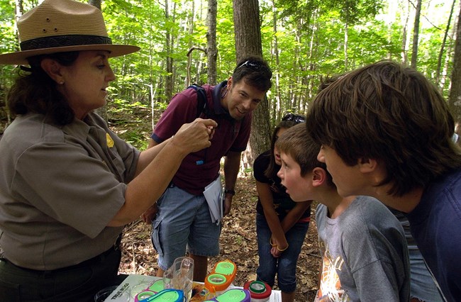A group of children and adult watch a park ranger demonstration. A group of children and adult watch a park ranger demonstration.