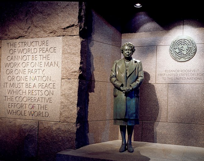 Photo of the statue of an older Eleanor Roosevelt with the United Nations seal in the background.