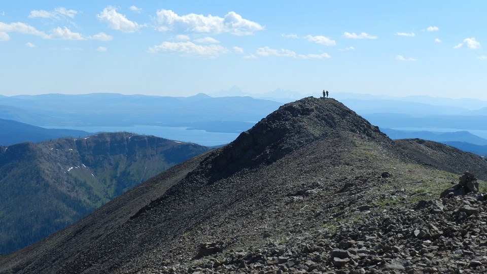 Two hikers standing on the rocky summit of Avalanche Peak Two hikers standing on the rocky summit of Avalanche Peak