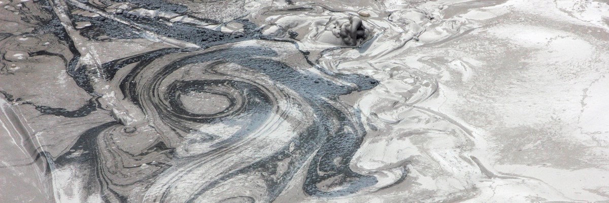 Swirls of black, gray, and white in a bubbling mudpot.