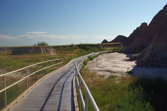 boardwalk trail in between prairie on the left and badlands formations on the right