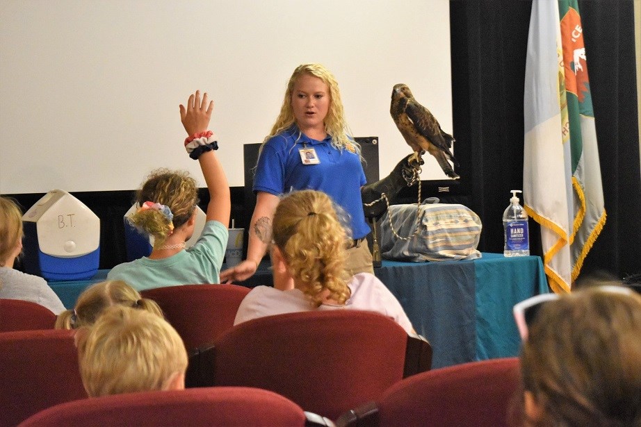 Woman holding hawk in front of children