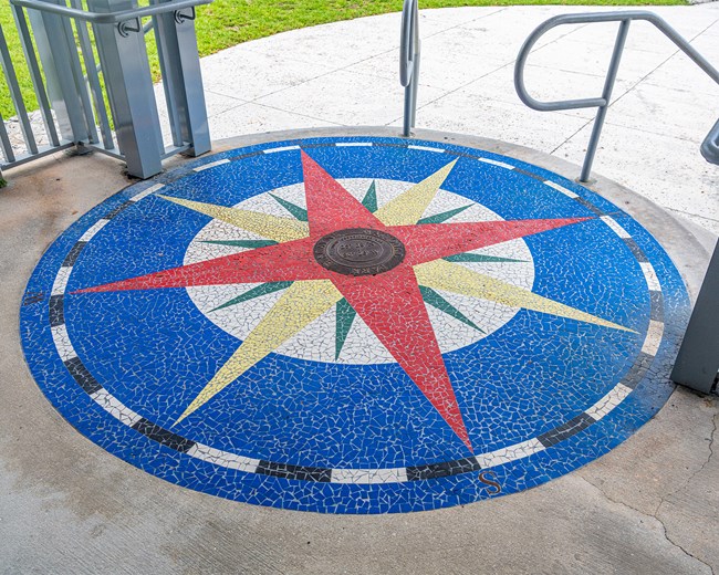 Blue, green, yellow, and red mosaic of a compass rose