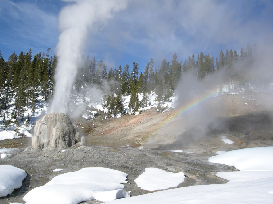 Lone Star Geyser erupting in winter with a rainbow captured in the spray. Lone Star Geyser erupting in winter with a rainbow captured in the spray.