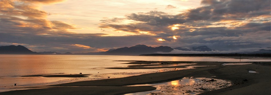 a dramatic sunset over a beach and mountains a dramatic sunset over a beach and mountains