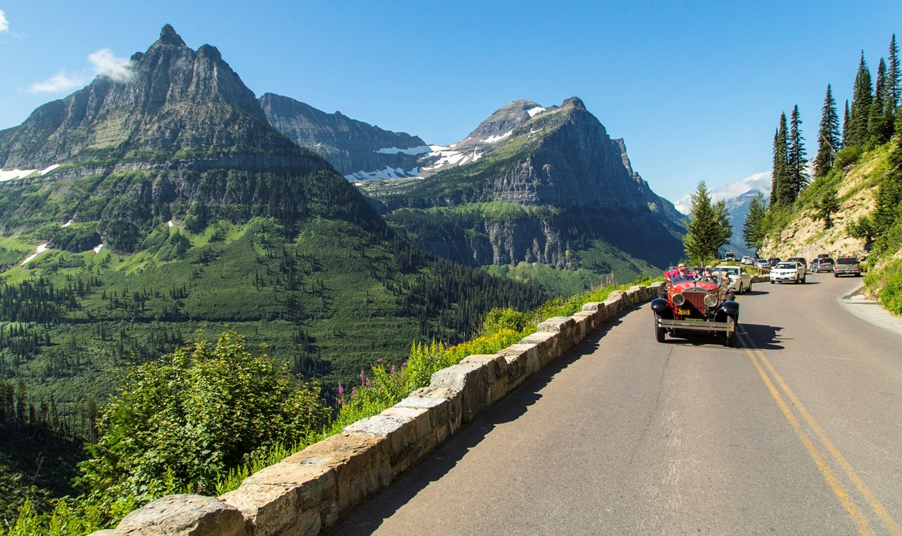 Antique car on road, dwarfed by mountain vista