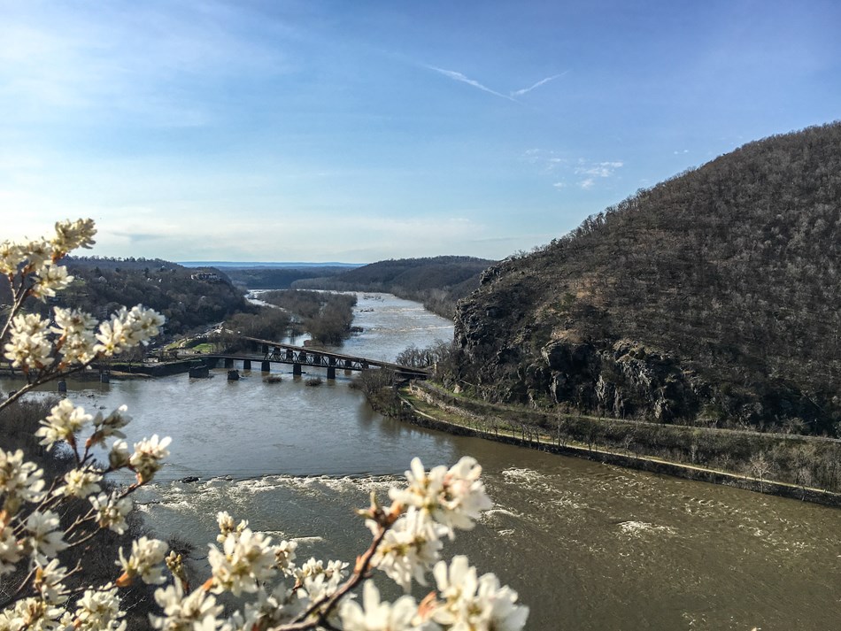 A sweeping view of two rivers meeting, a railroad bridge crossing over the river to arrive in a hilltop town A sweeping view of two rivers meeting, a railroad bridge crossing over the river to arrive in a hilltop town