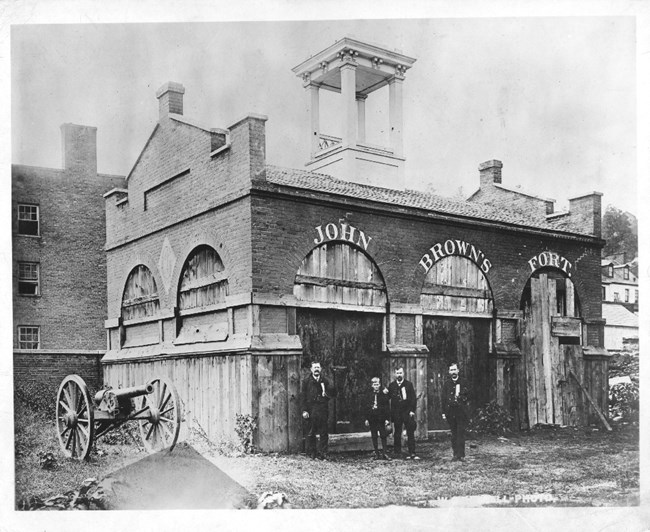 black and white photo, ca. 1886-89 of men standing in front of John Brown's Fort