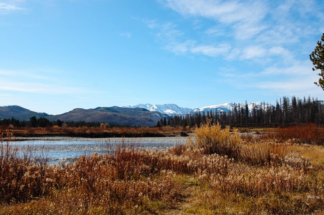 Grassy Lake Road A river with mountains in the background.