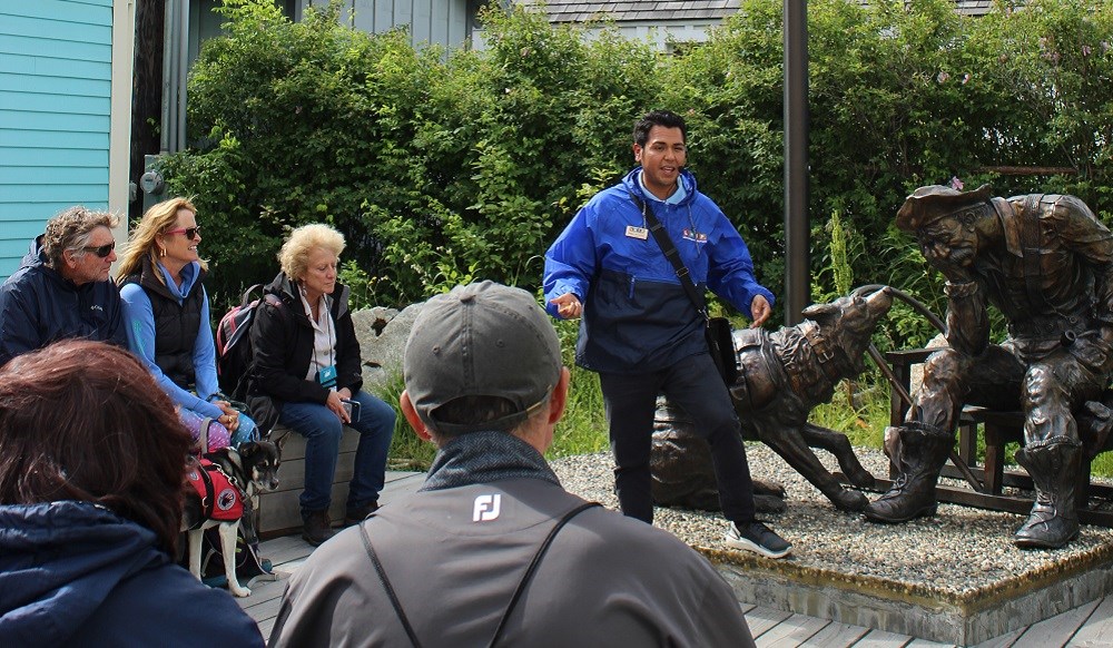 A group of people gather around the gold prospector statue during a historic walking tour A group of people gather around the gold prospector statue during a historic walking tour