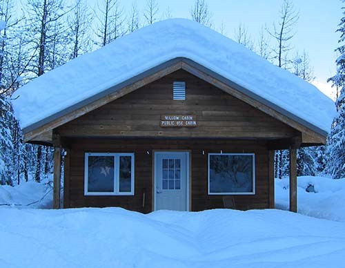 Snow covered, wooden cabin.