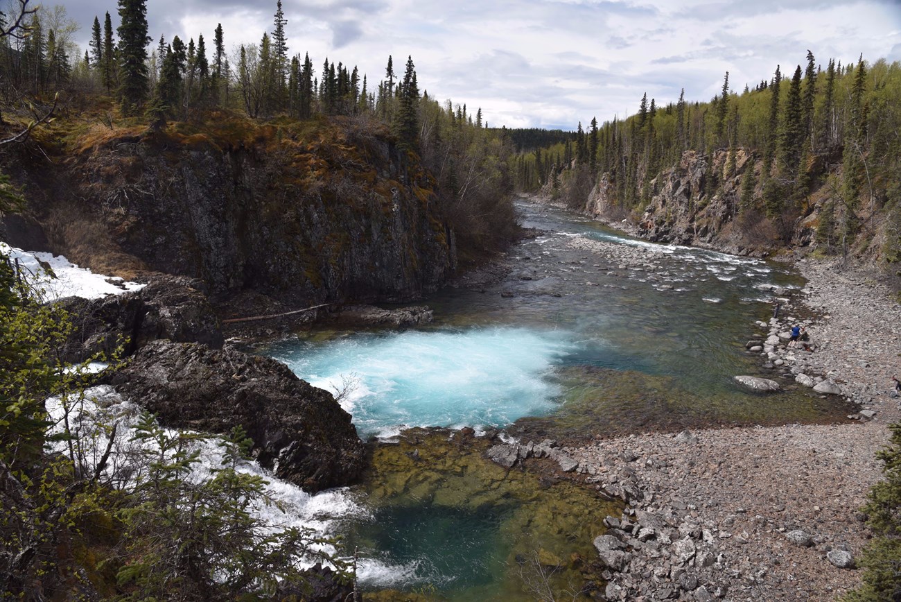 A view of the Tanalian River from ontop of the waterfall. People are fishing along the bank.