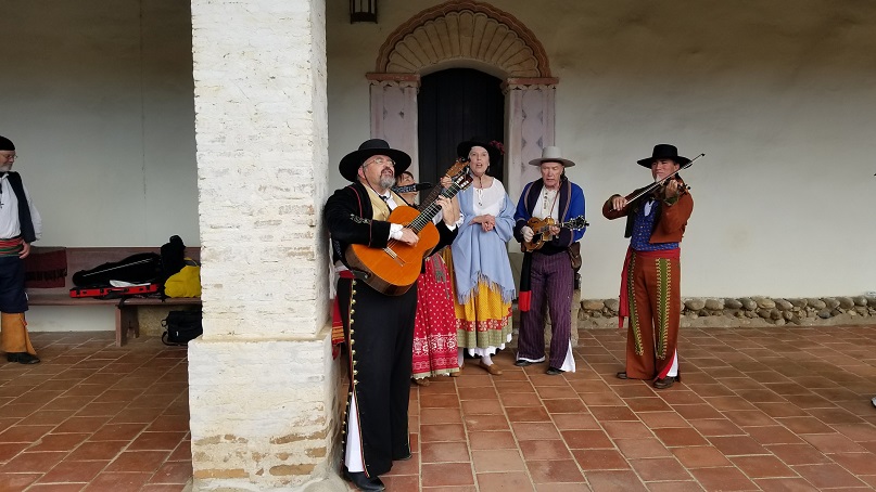Musicians dressed in 18th Century era Spanish clothing with musical instruments.