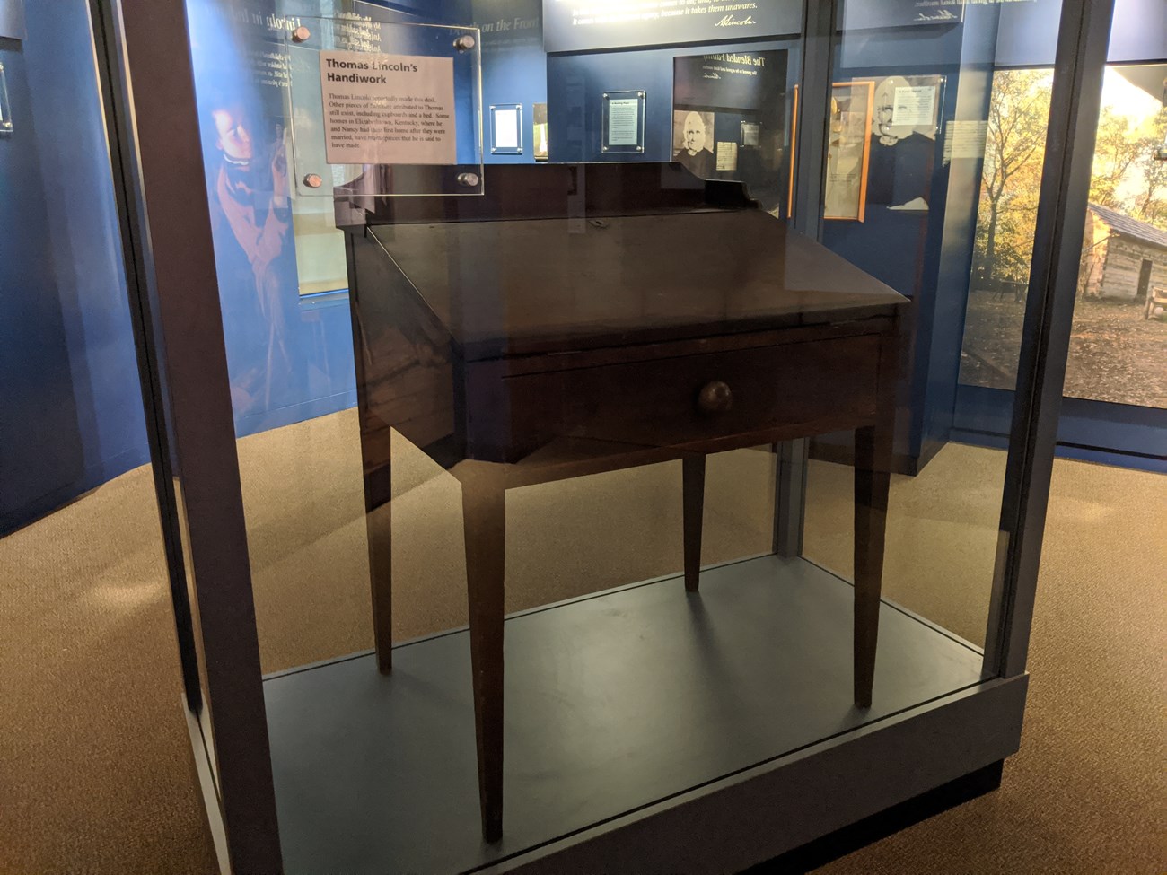 Wooden desk in glass display case.