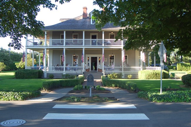 Photo of the Grant House, a grey two-story house with a veranda decorated with American flags.