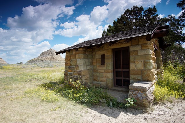 Tree behind stone structure with wood roof.