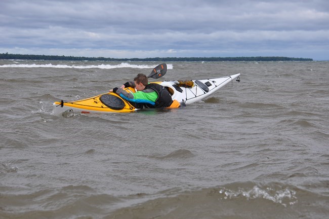 Image of kayaker conducting a self rescue into their kayak