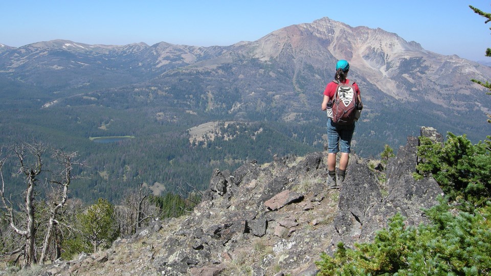 Hiker looking at a mountain Woman hiker wearing a small backpack looks out at a nearby mountain.