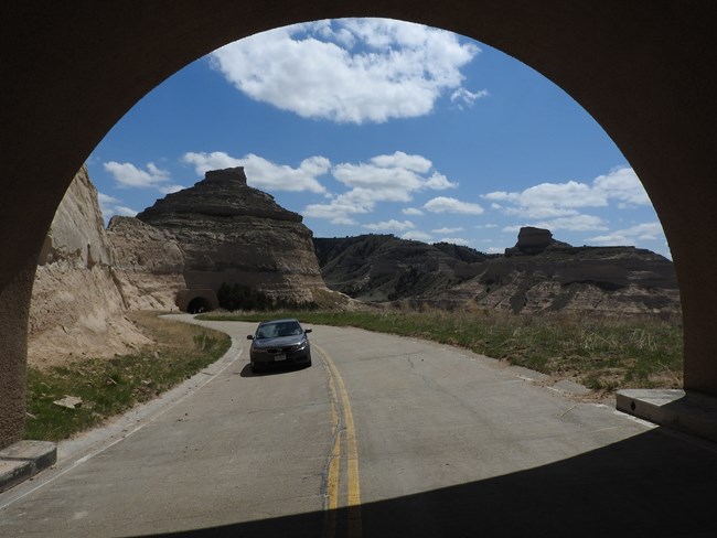 A car approaches a tunnel on steep, winding road