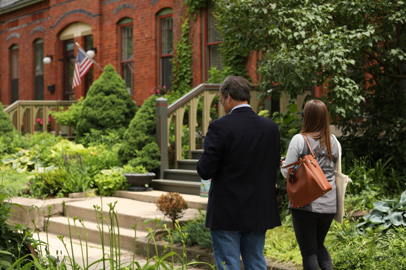Two visitors walk past historic red brick row houses.