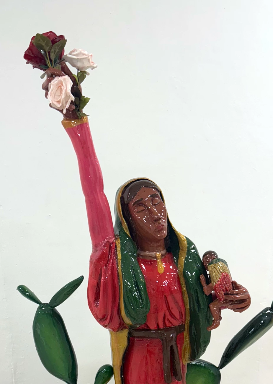 Volver 2024 by Priscila Ortiz Sculpure of a feminine figure holding roses and an angel