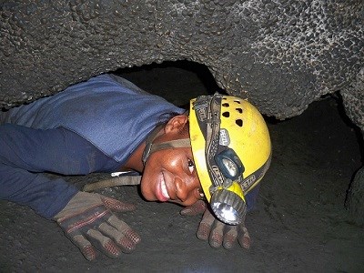 Caver in a tight squeeze in cave