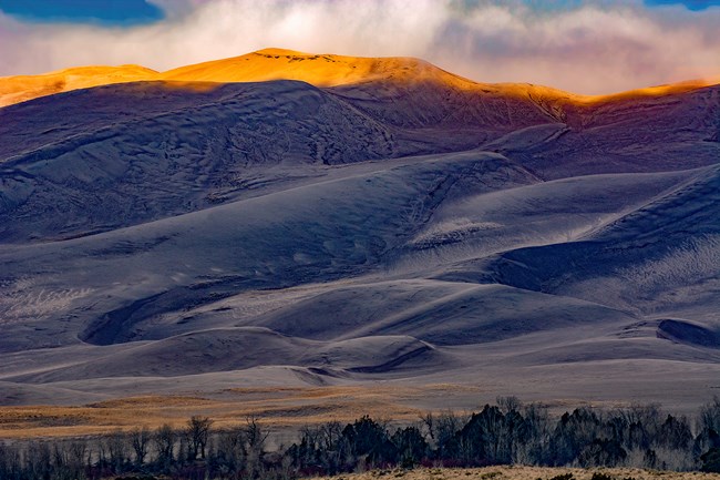 Morning light strikes the top of a ridge of dunes
