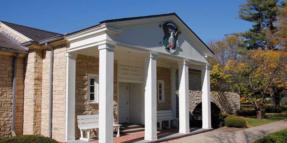 A white museum portico has a presidential seal mounted on the pediment. A white museum portico has a presidential seal mounted on the pediment.