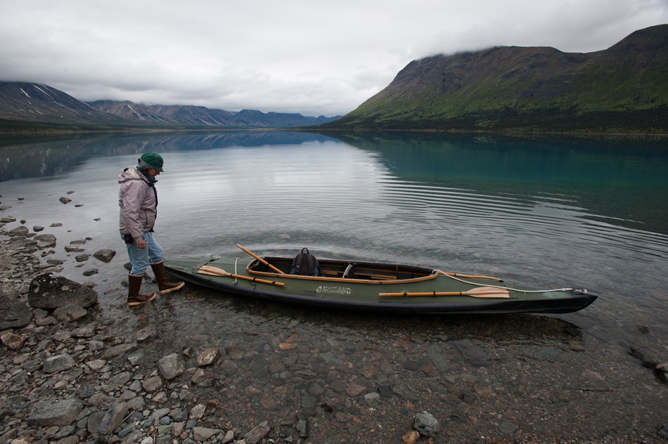 a park volunteer walks near a kayak on the shore of upper twin lake. a park volunteer walks near a kayak on the shore of upper twin lake.