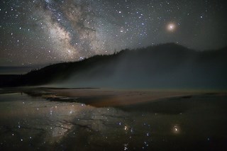 A galaxy of stars over a mountainous landscape