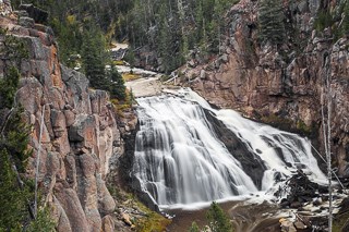 A waterfall drops over a steep rock surface.