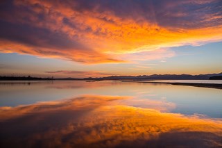 A sunrise is reflected in a body of water.