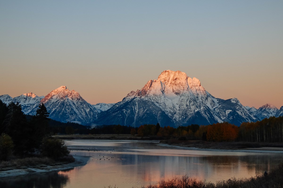 Oxbow Bend Sunrise on a snowy mountain with a river in the foreground.