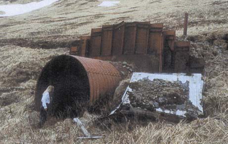 a woman enters a large rusted tube coming out of the ground