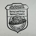 An ink stamp of a badge with a flat hat and the text Junior Ranger, Bering Land Bridge National Preserve.