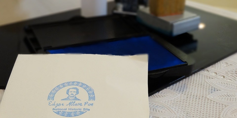 Edgar Allan Poe stamp Color image of a blue stamp depicting Poe on a white piece of paper.