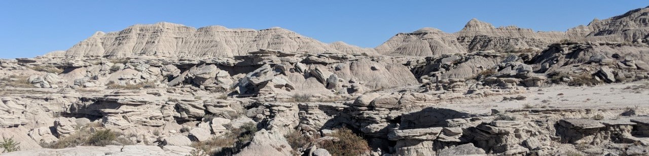 a vast landscape of eroded buttes, layered with more resistant sandstone boulders.