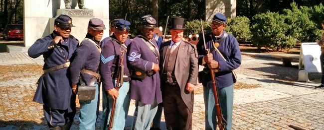 Volunteers dressed as Buffalo Soldiers with Theodore Roosevelt reenactor.