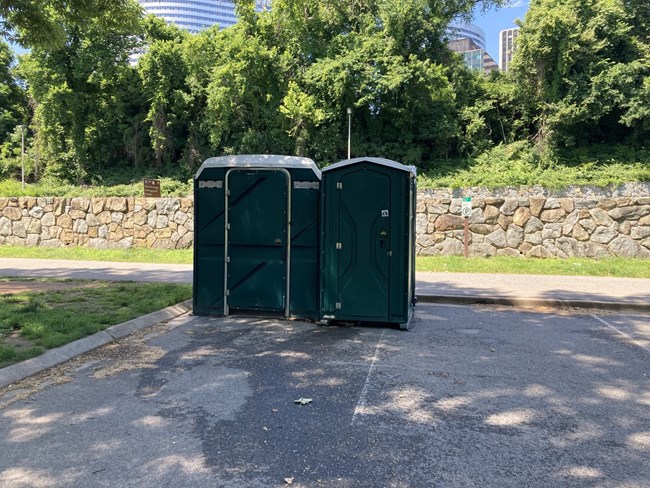Two portapotties in a parking lot.