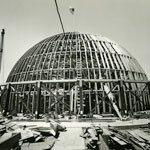 US flag flies over shell of memorial dome.  black and white photo.